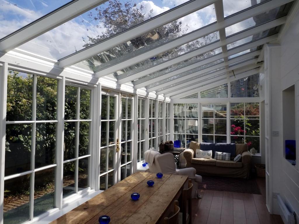 ein Wintergarten mit Glasdecke und einem Holztisch in der Unterkunft The Vintage - A Hidden Gem close to the Old Course in St Andrews