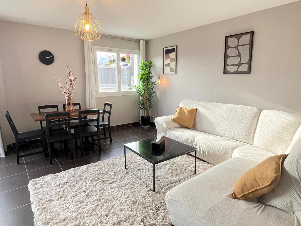 a living room with a white couch and a table at Maison moderne avec terrasse & parking in Clermont-Ferrand