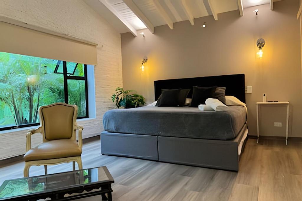 a bedroom with a large bed and a chair at Apto BR Suites 6 min de Provenza, encanto natural in Medellín