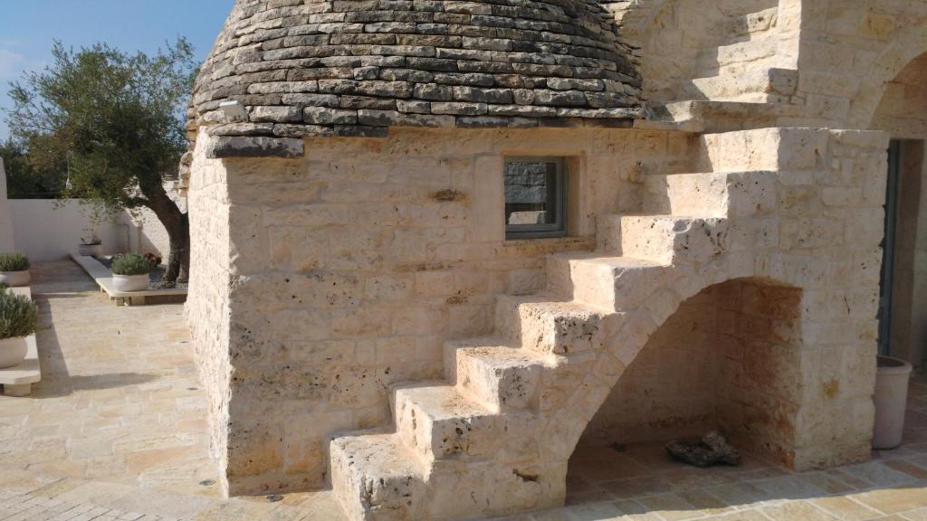 a stone building with a staircase in a courtyard at Dimora Sumerano in Alberobello