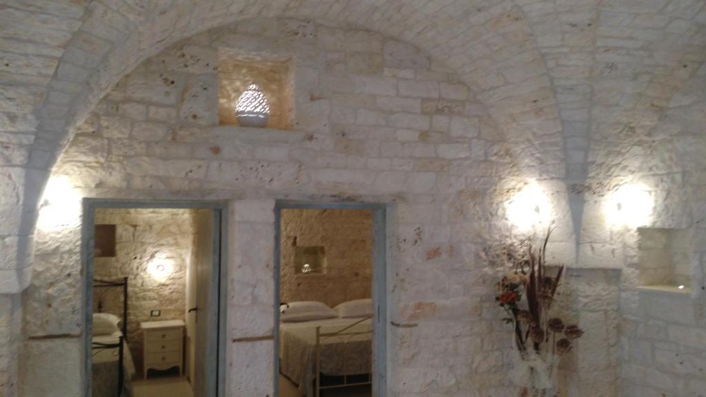a room with a stone wall with a bedroom at Dimora Sumerano in Alberobello
