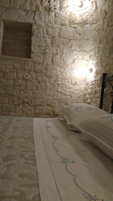 a bedroom with a bed in a stone wall at Dimora Sumerano in Alberobello