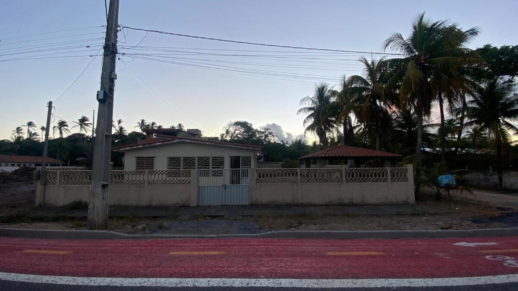 a house on a street with a fence and palm trees at Casa Aver o Mar in Sirinhaém
