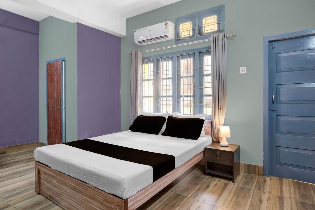 een slaapkamer met een bed en een blauwe muur bij Hotel O Junaki Inn in Guwahati