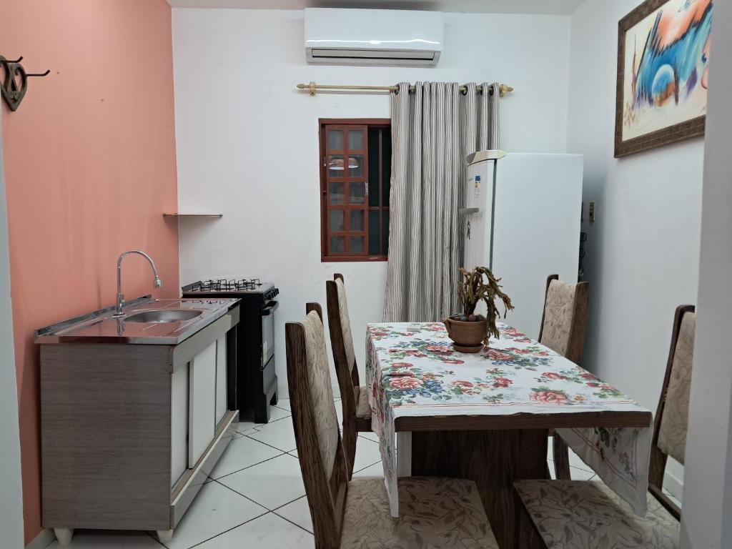 a kitchen with a table and a sink and a refrigerator at kitnet Ceu in Campo Grande