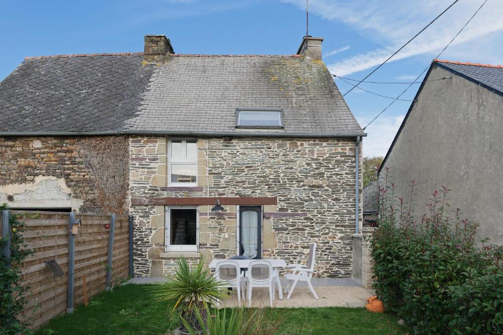 a small stone house with two chairs and a table at Gîte l'orée de la forêt légendaire in Néant-sur-Yvel