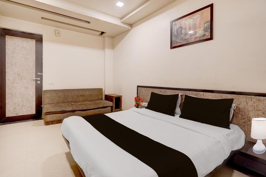 a bedroom with a large bed and a chair at Hotel O Vatva Railway Station Formerly Anmol Palace in Ahmedabad
