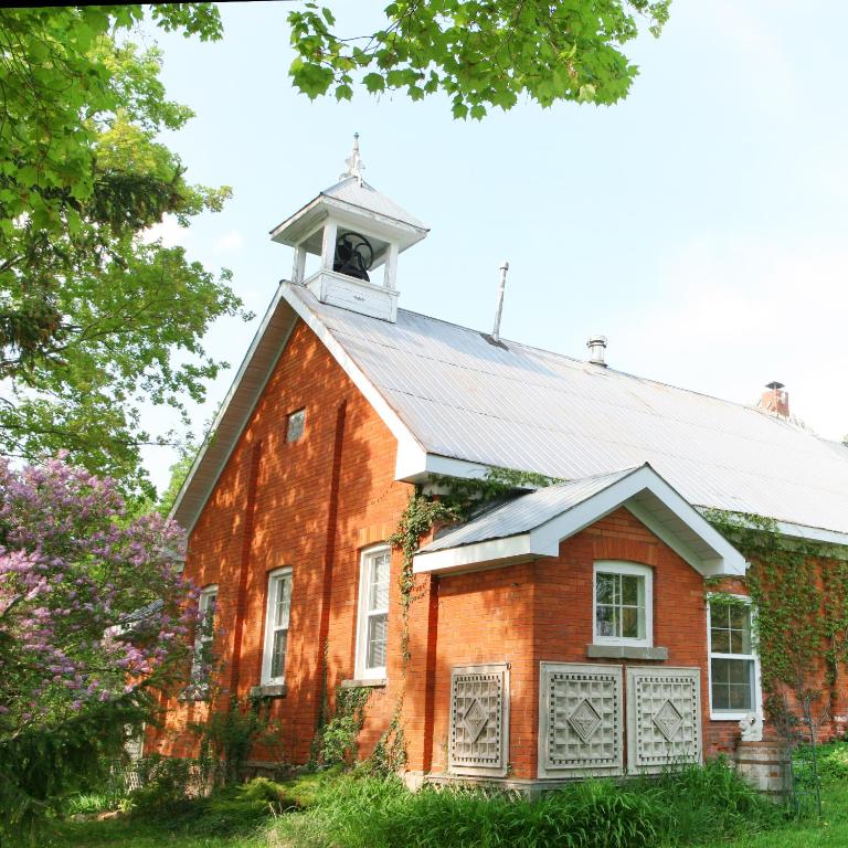a red brick building with a clock tower on top at Picturesque School House Retreat in Meaford