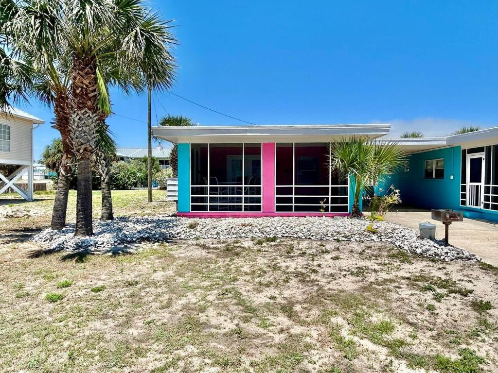 een huis met een roze deur en palmbomen bij Baked Beach Bungalow in St. George Island