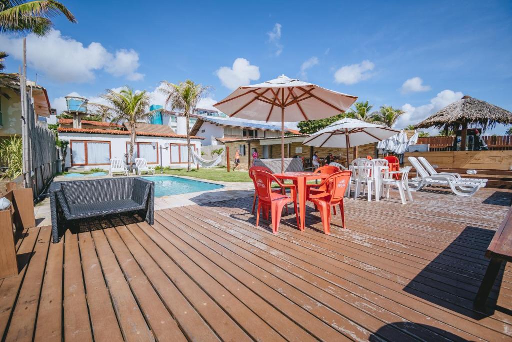 a deck with a table and chairs and an umbrella at Mar a Vista by Concavus in Porto De Galinhas