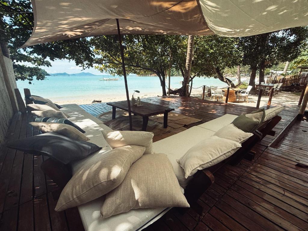 un groupe de coussins posés sur une terrasse donnant sur la plage dans l'établissement BAIA - Beachfront Boutique Lodge in San Vicente, Palawan, à San Vicente