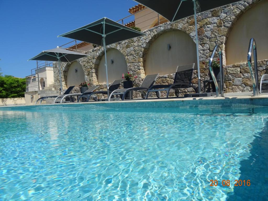 a large swimming pool with chairs and umbrellas at Villa la Vista in Lumio