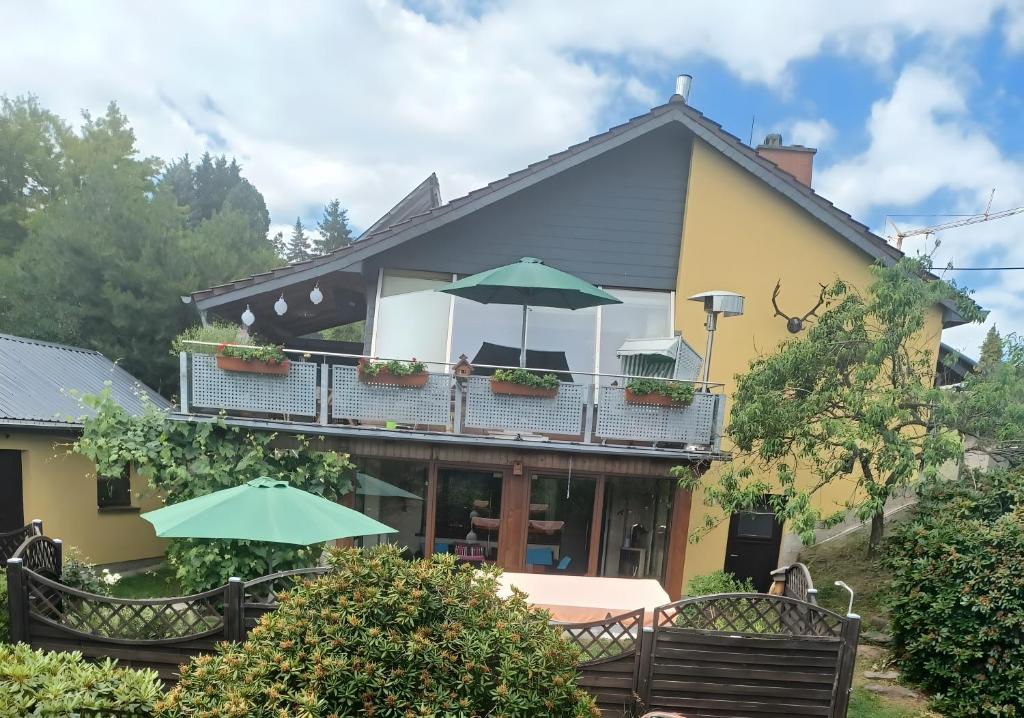 une maison dotée d'un balcon avec des parasols dans l'établissement Ferienwohnung Heidi, à Bielatal