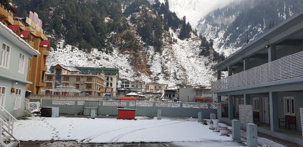 une ville avec des bâtiments et une montagne enneigée dans l'établissement Naran Mountain Chalets, à Dargai