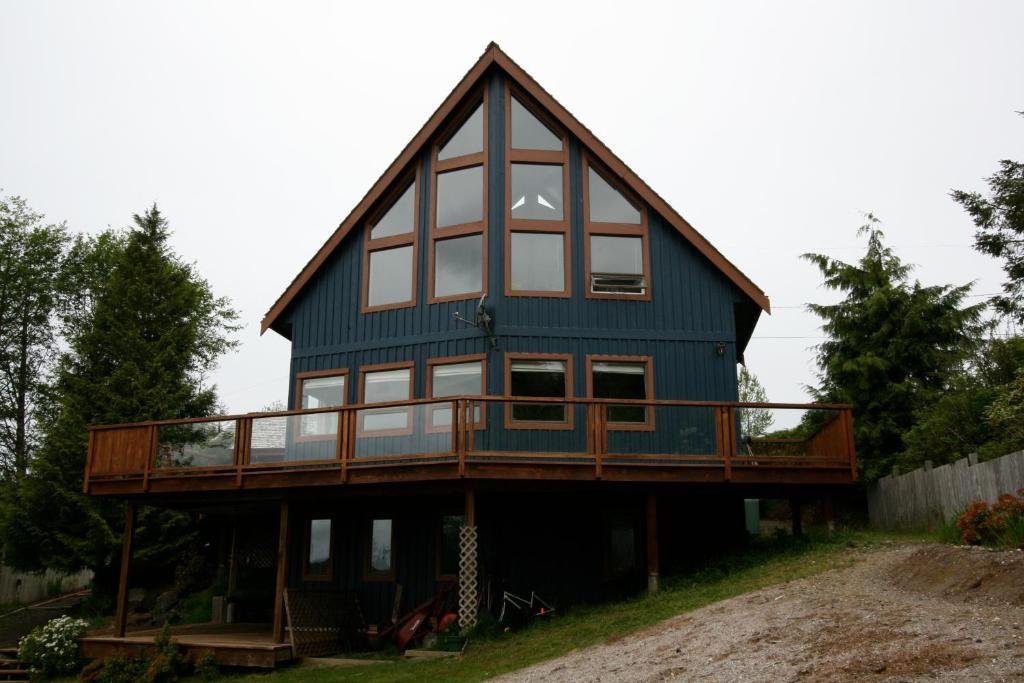 a house with a wrap around porch and a deck at Moon and Sixpence in Ucluelet