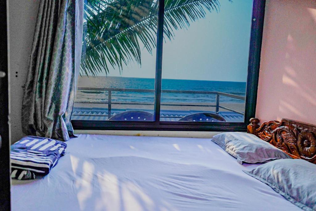 a bedroom with a bed with a view of the beach at coastal beach front stay in Gokarna