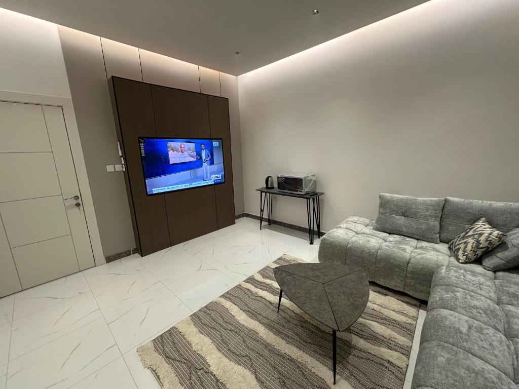 a living room with a couch and a flat screen tv at جناح عائلي غرفة وصول ذاتي in Al Hofuf