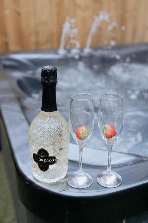 a bottle of wine and three wine glasses on a tray at Marine Cottage 1 - With Private Hot Tub in Newbiggin-by-the-Sea