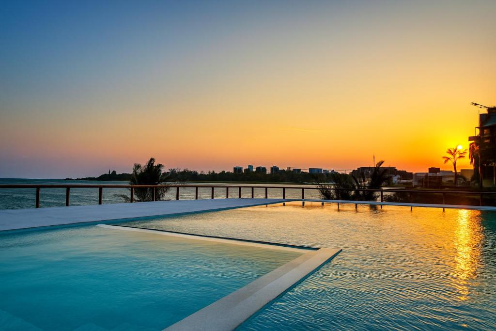 una piscina a sfioro con il tramonto sullo sfondo di Casa Del Mar Villa by YourHost 5B – Nyali Mombasa a Mombasa