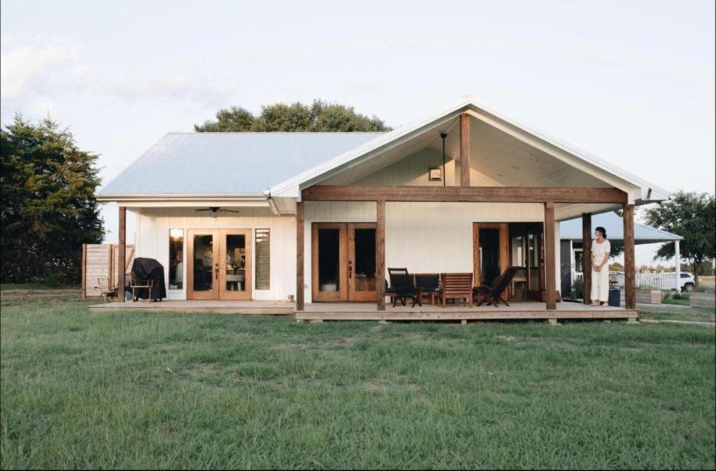 Eine Frau, die vor einem Haus steht. in der Unterkunft Modern Luxury Rental with Bohemian Decor near Antique Show in Round Top, Texas in Round Top