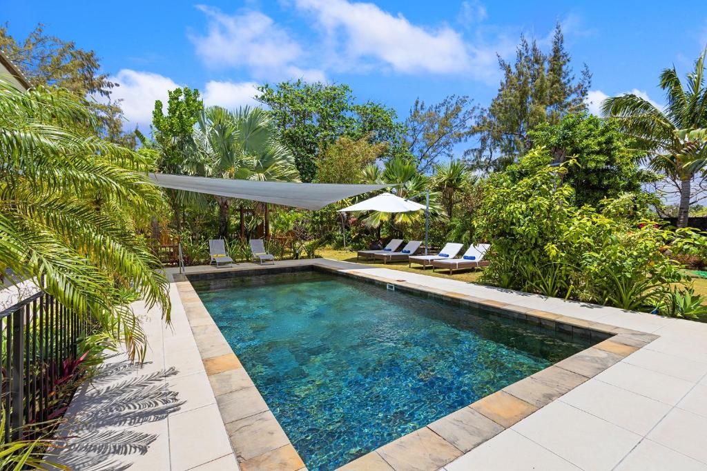 a swimming pool in a yard with chairs and an umbrella at Croix Du Sud by Host Agents in Palmar