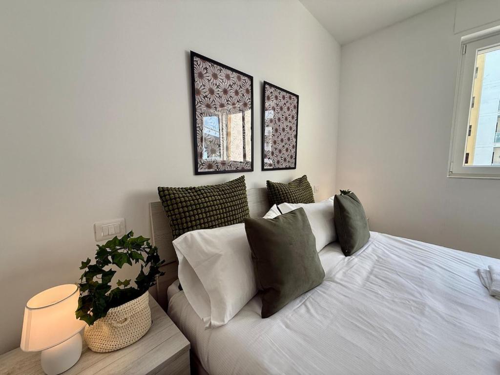 1 dormitorio con cama blanca y almohadas verdes en Suite dei Principi 2, aeroporto e parcheggio gratuito, en Bari