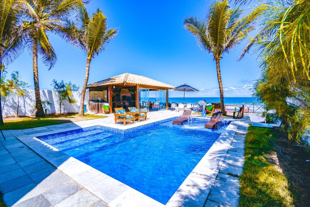 a swimming pool with palm trees and a gazebo at Mar a Vista Charme by Concavus in Porto De Galinhas