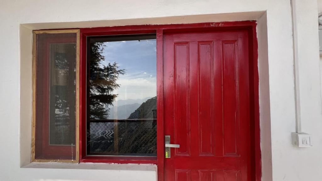 una puerta roja con vistas a una montaña en Jaberkhet Trekkers Lodge, en Mussoorie