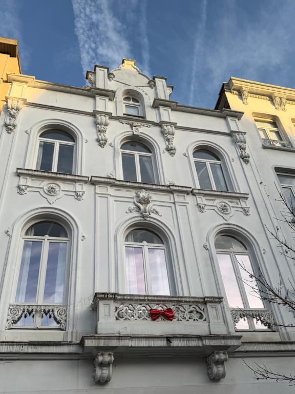 een wit gebouw met een balkon met een rode strik bij Mansion RL with Unique Decoration in Antwerpen