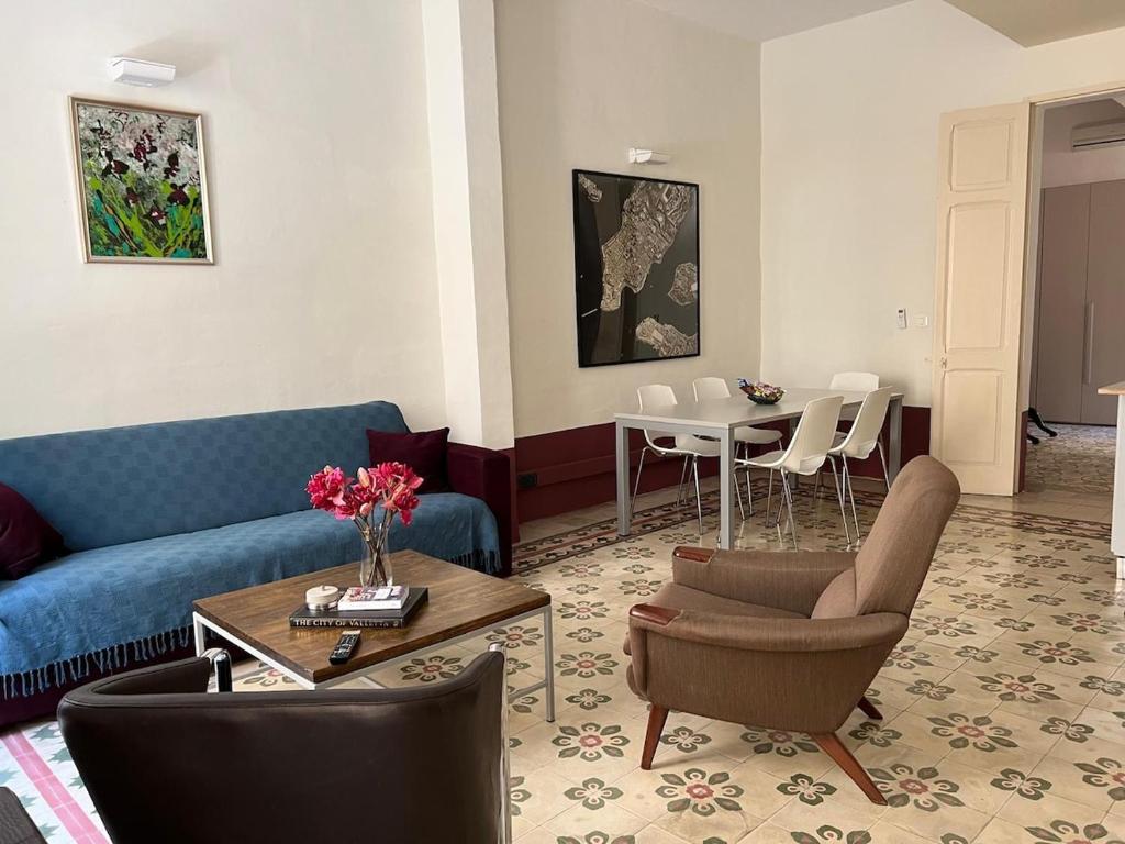 a living room with a blue couch and a table at Charming Apartment in the Heart of Valletta in Valletta