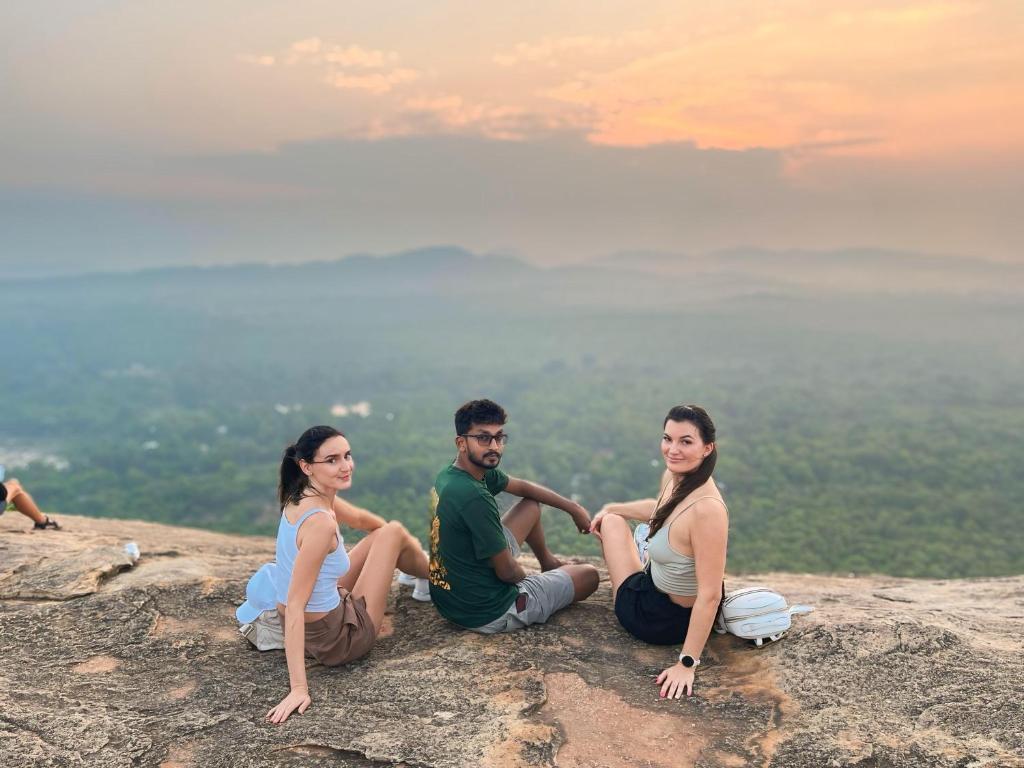 a group of three people sitting on top of a mountain at Sigiri Serenity Hostel in Sigiriya