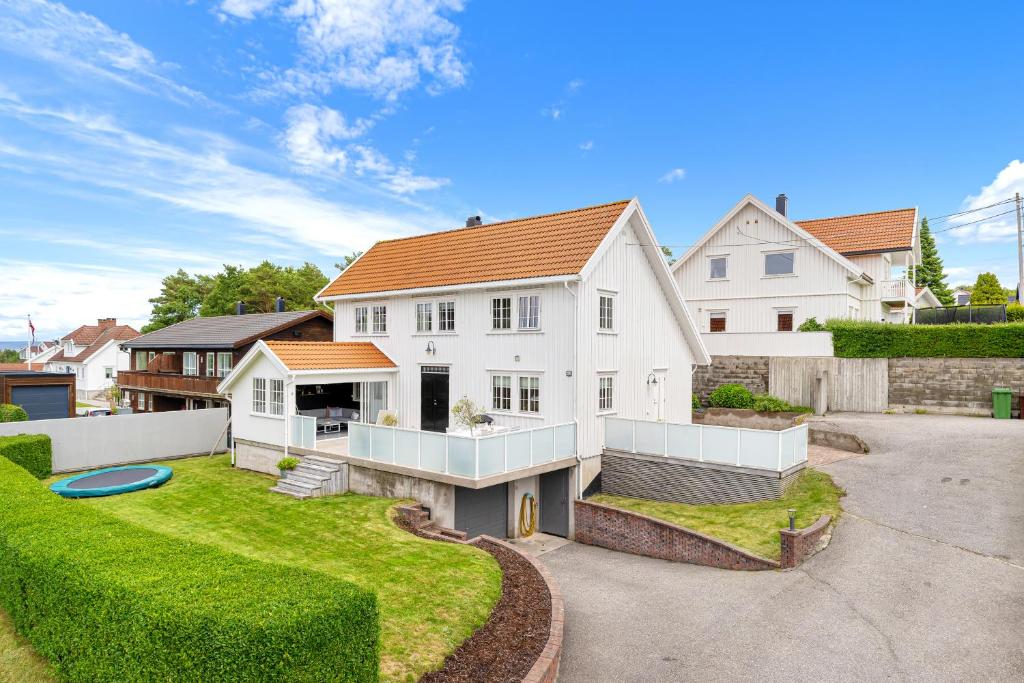 ein großes weißes Haus mit einem angelegten Garten in der Unterkunft Feriehus med stort lekerom in Kristiansand