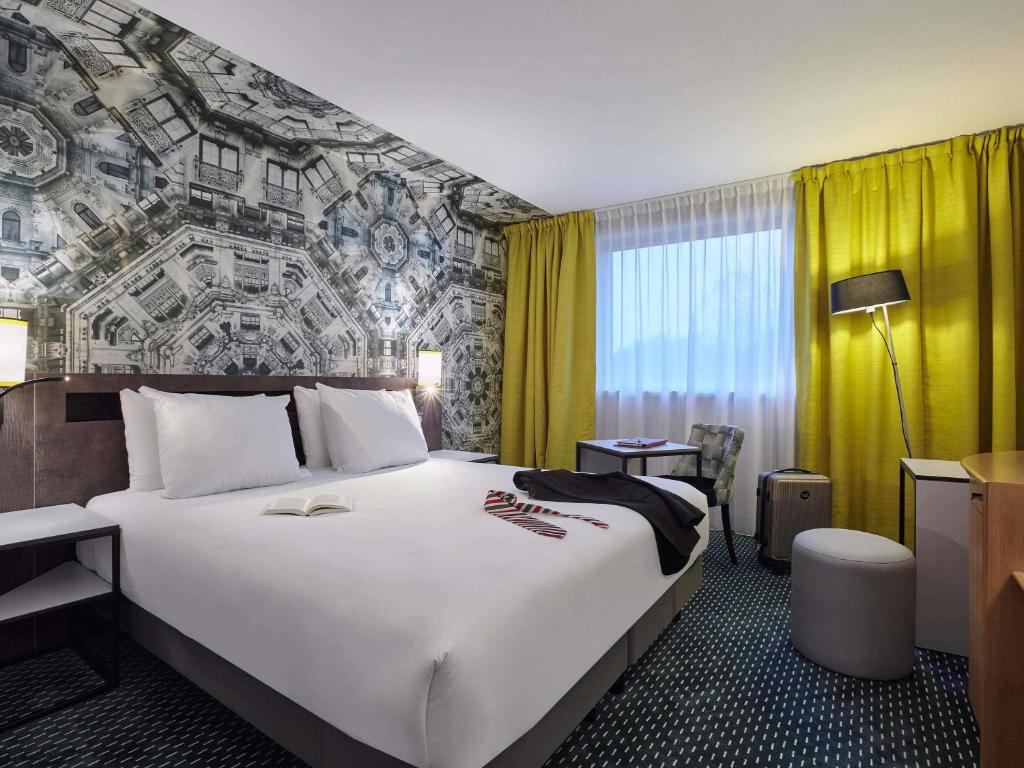 een hotelkamer met een groot bed en een gele muur bij Mercure Paris Roissy CDG in Roissy-en-France