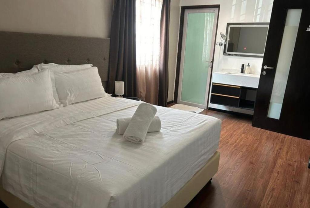 Schlafzimmer mit einem weißen Bett, einem Waschbecken und einem Spiegel in der Unterkunft King's Lane in Ipoh