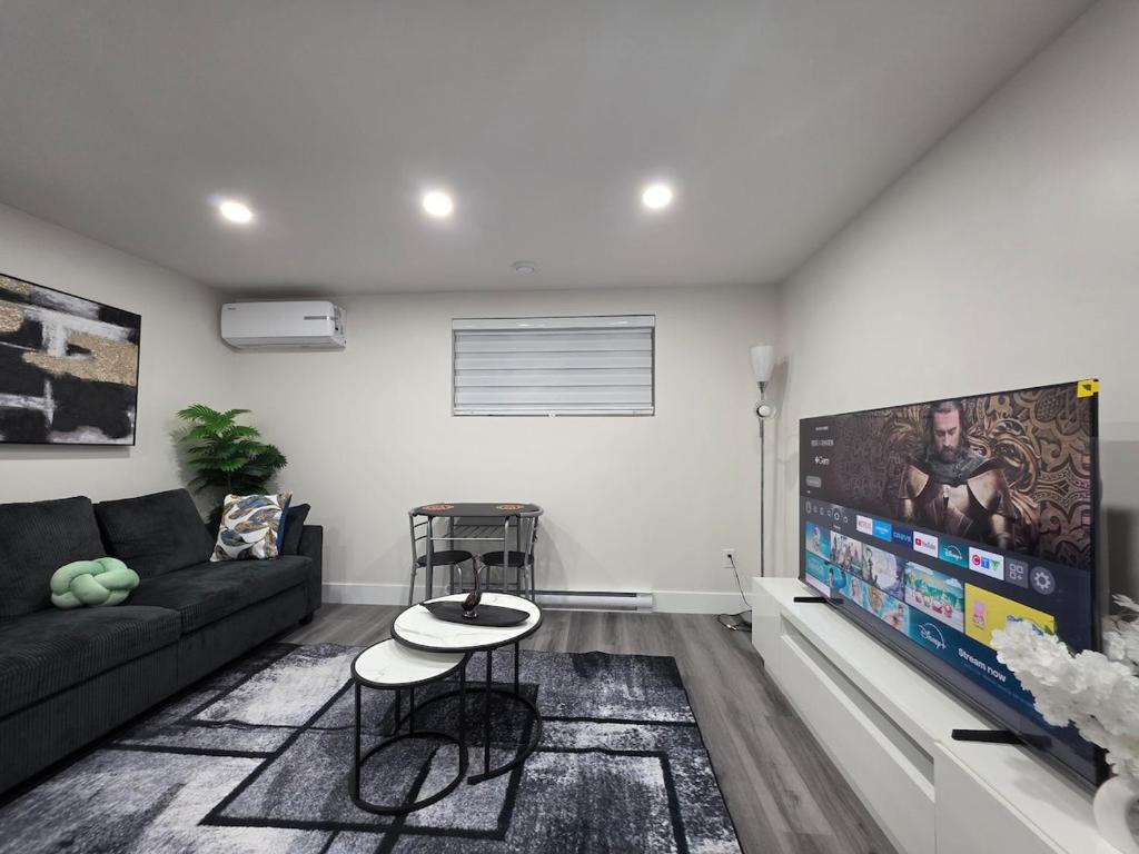 a living room with a couch and a flat screen tv at Cozy Haven Suite in Moncton