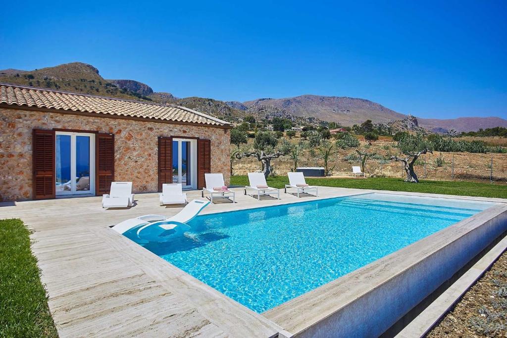 una piscina con sillas y una casa en VILLA DEL BORGO con piscina e jacuzzi, en Scopello