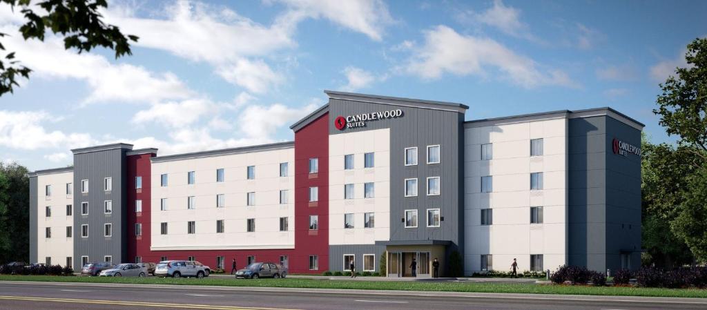 ein großes weißes und rotes Gebäude mit draußen geparkt in der Unterkunft Candlewood Suites Mankato East by IHG in Mankato
