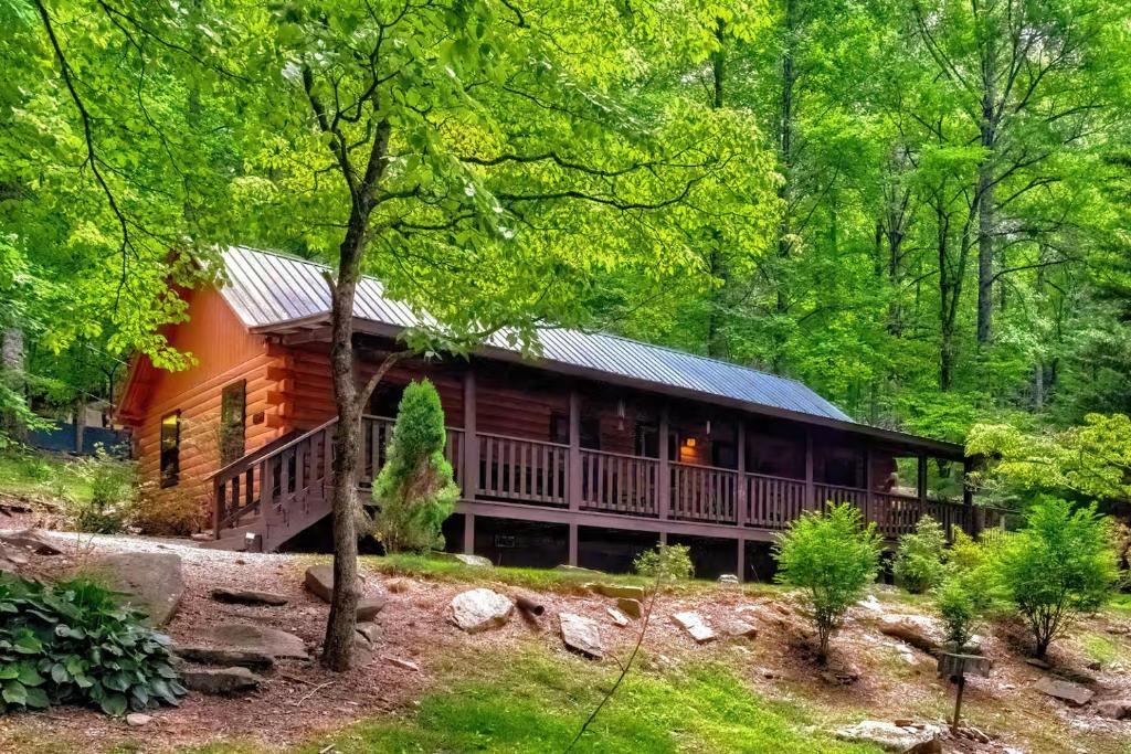 eine Blockhütte im Wald mit Bäumen in der Unterkunft Lovely Rustic Cabin Secluded in the Woods near Maggie Valley, North Carolina in Cherokee