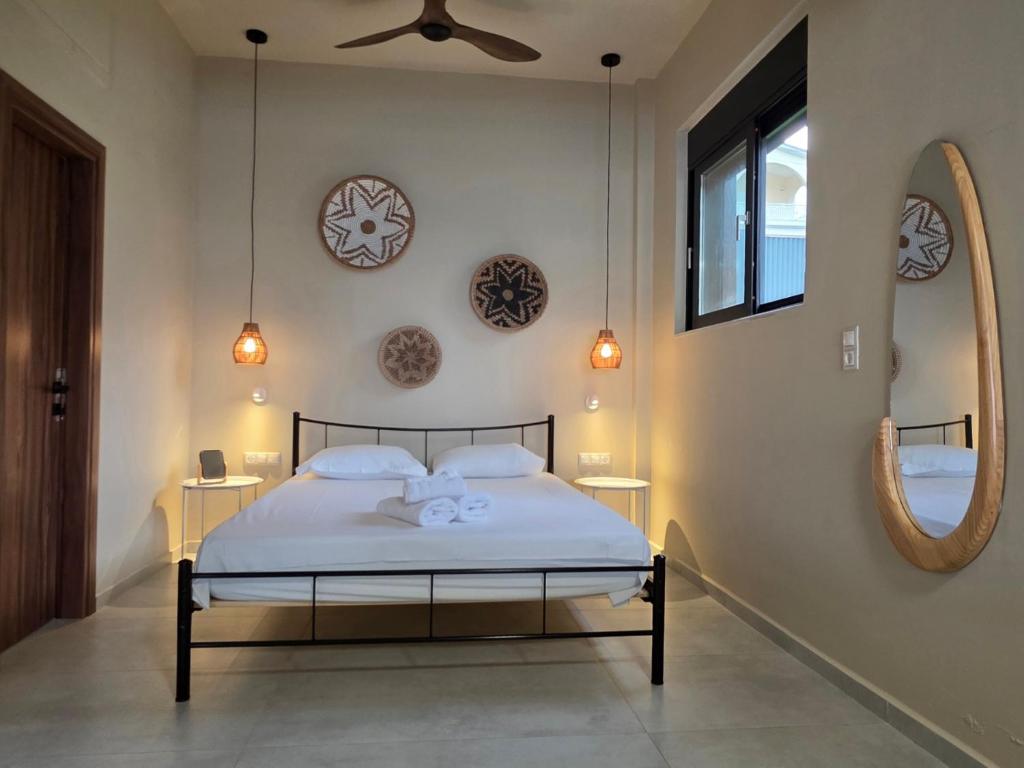 a bedroom with a bed with white sheets and clocks on the wall at Rastoni Studio Xylokastro 2 in Melission
