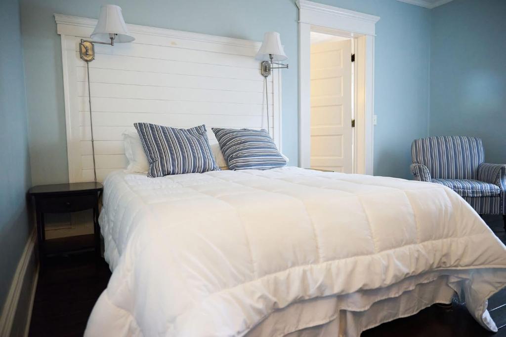 a bedroom with a white bed and a chair at The Inn At The Bridge in Northville