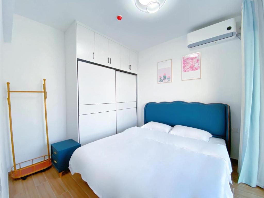 a bedroom with a large bed with a blue headboard at Nearby Time in Beihai