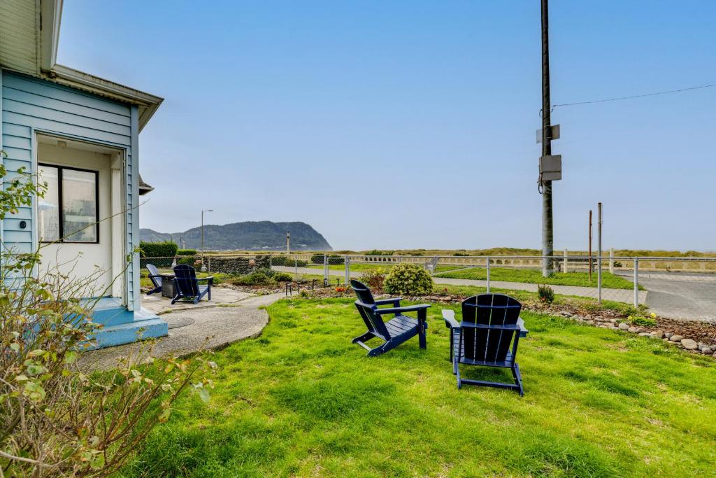 a group of chairs sitting in the grass next to a house at Beachfront Cottage on Seaside Promenade with Hot Tub in Seaside
