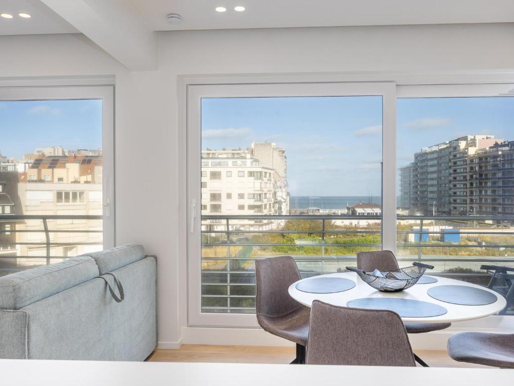a living room with a table and chairs and a large window at Wimbledon Westende - 0306 + box 10 in Westende-Bad