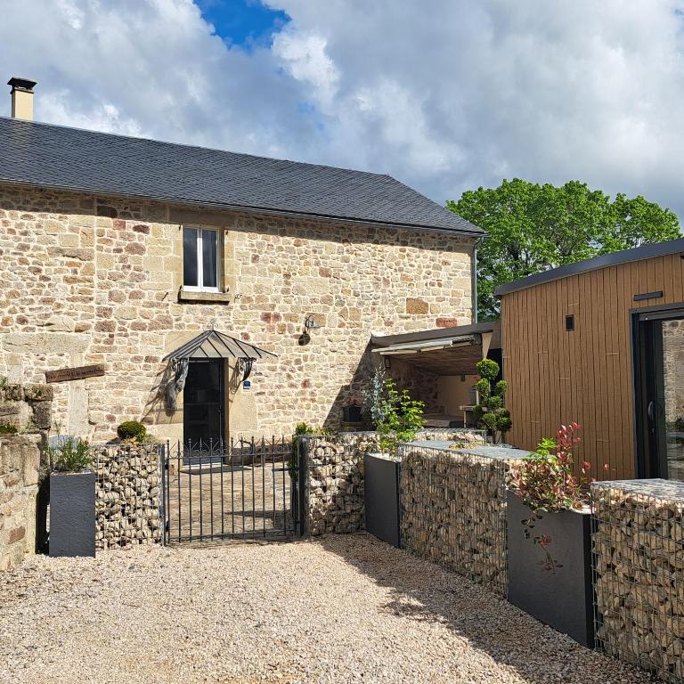 a brick house with a fence in front of it at Le Crochet de Pervenche in Recoules-Prévinquières