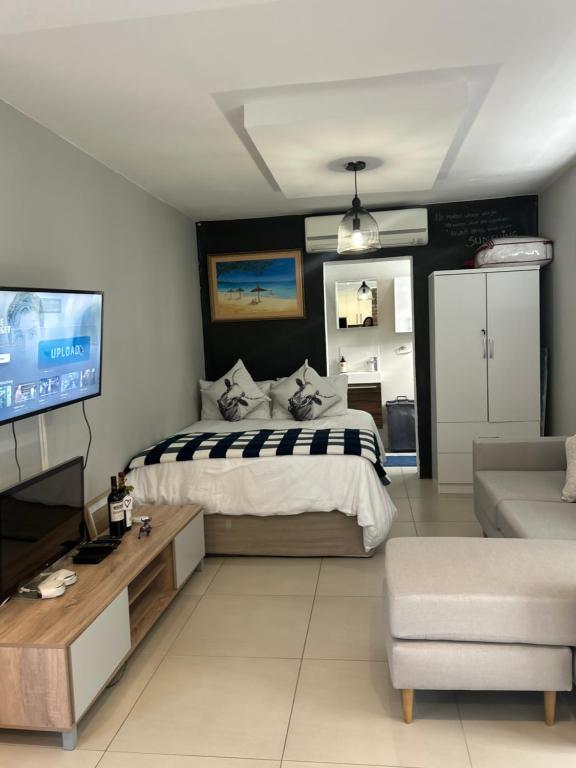 a bedroom with a bed and a tv and a couch at Home Away From Home 6 minutes away from beach in Cape Town