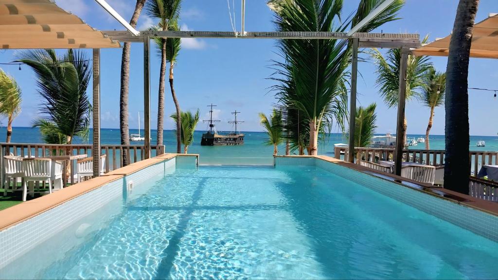 ein Swimmingpool mit Palmen und dem Meer in der Unterkunft Punta Cana Beach & Garden B&B 1 in Punta Cana