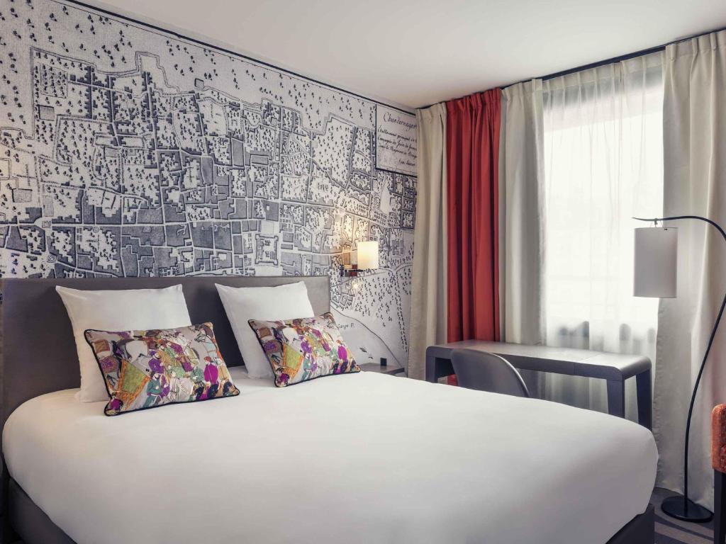 a bedroom with a large white bed and a wall at Mercure Tour Eiffel Grenelle in Paris