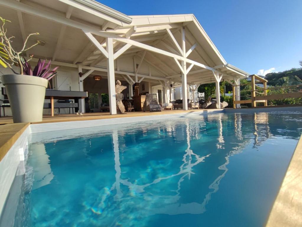 an outdoor swimming pool with a pergola and blue water at Villa Franco - Plage de Leroux à 600m - Vue mer exceptionnelle in Deshaies