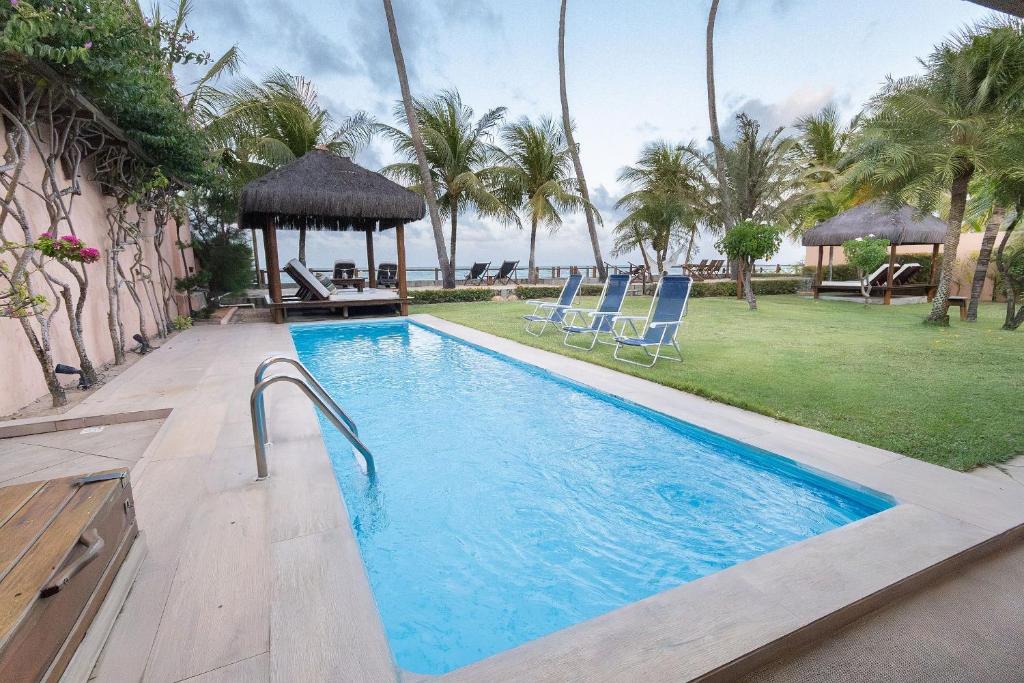 ein Swimmingpool mit Stühlen und einem Pavillon in der Unterkunft Casa Mar: vista e acesso à praia | By Carpediem in Jacumã