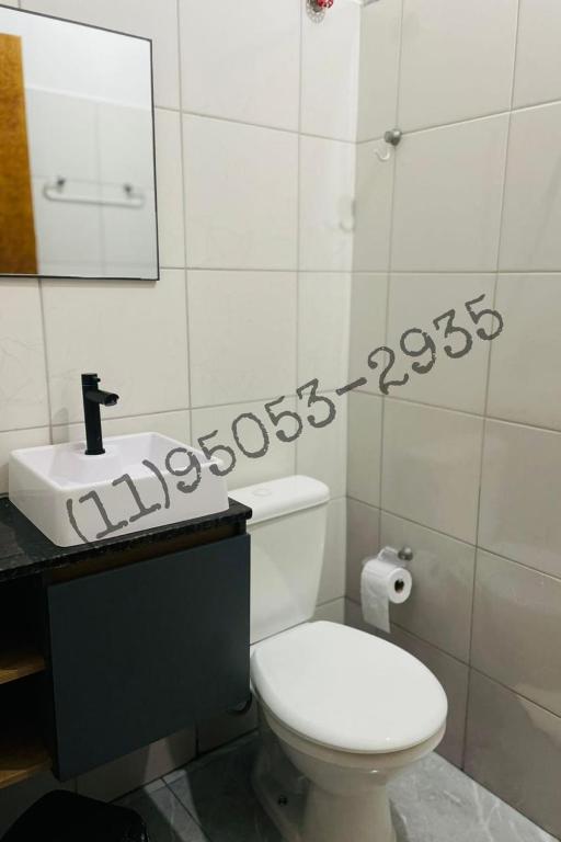 a bathroom with a white toilet and a sink at Bertioga Rio da Praia in Bertioga